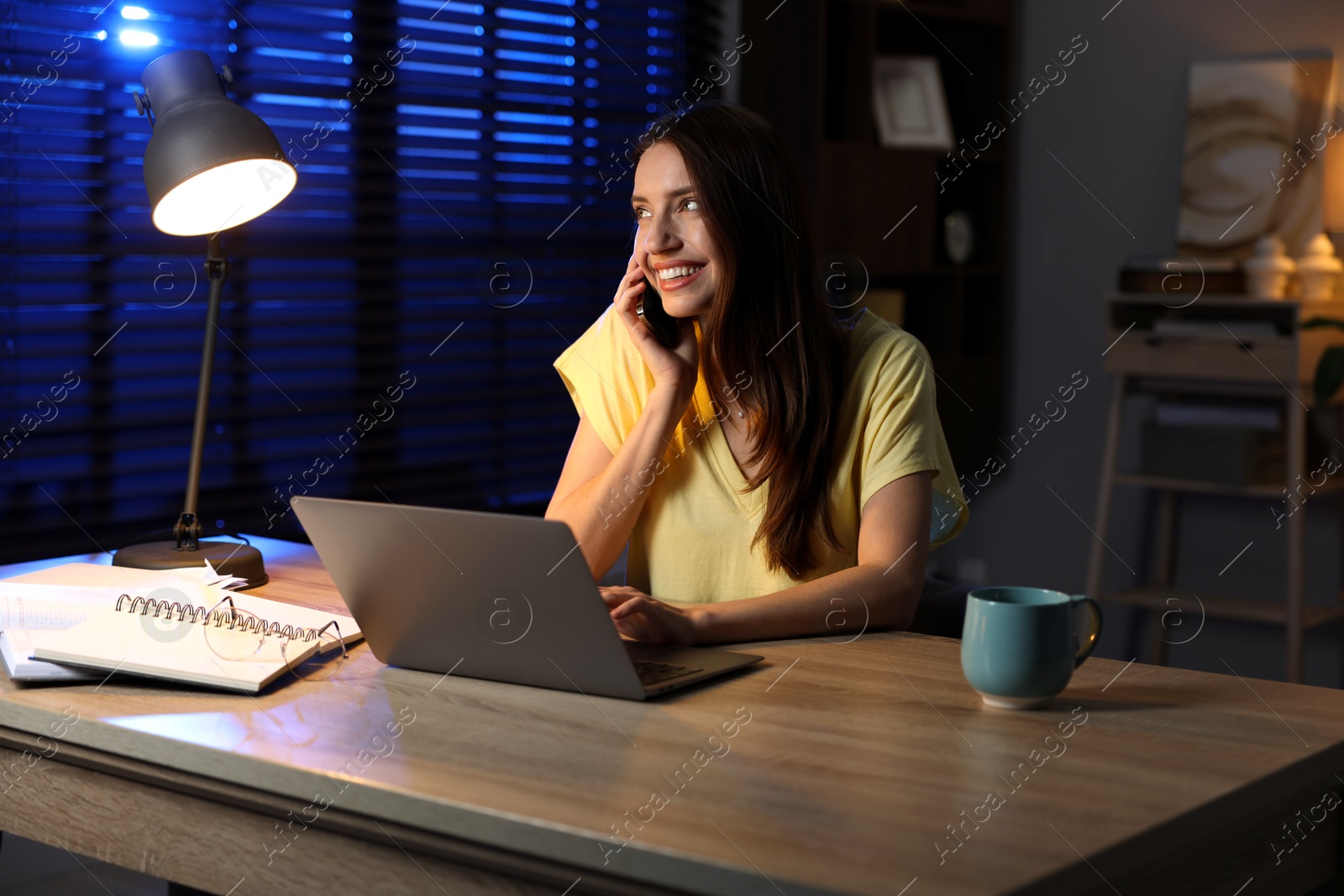 Photo of Woman talking on phone while working at desk in home office