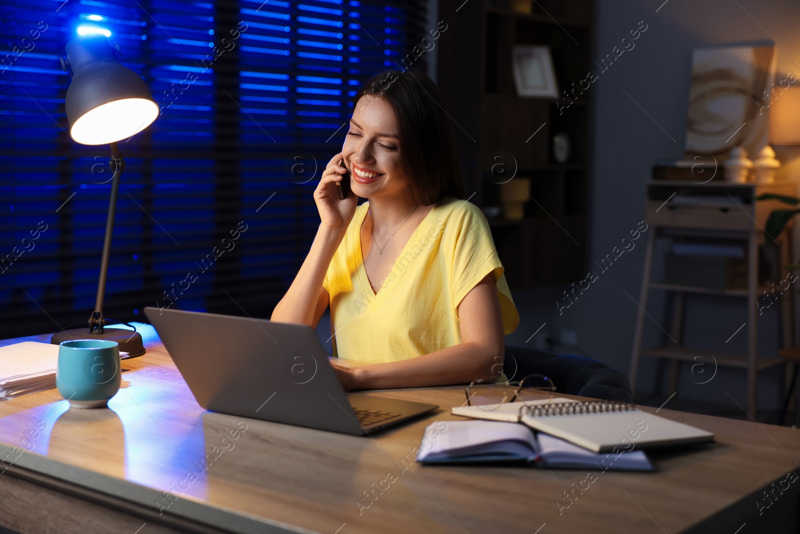 Photo of Woman talking on phone while working at desk in home office