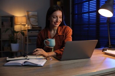 Photo of Woman taking notes while working at desk in home office