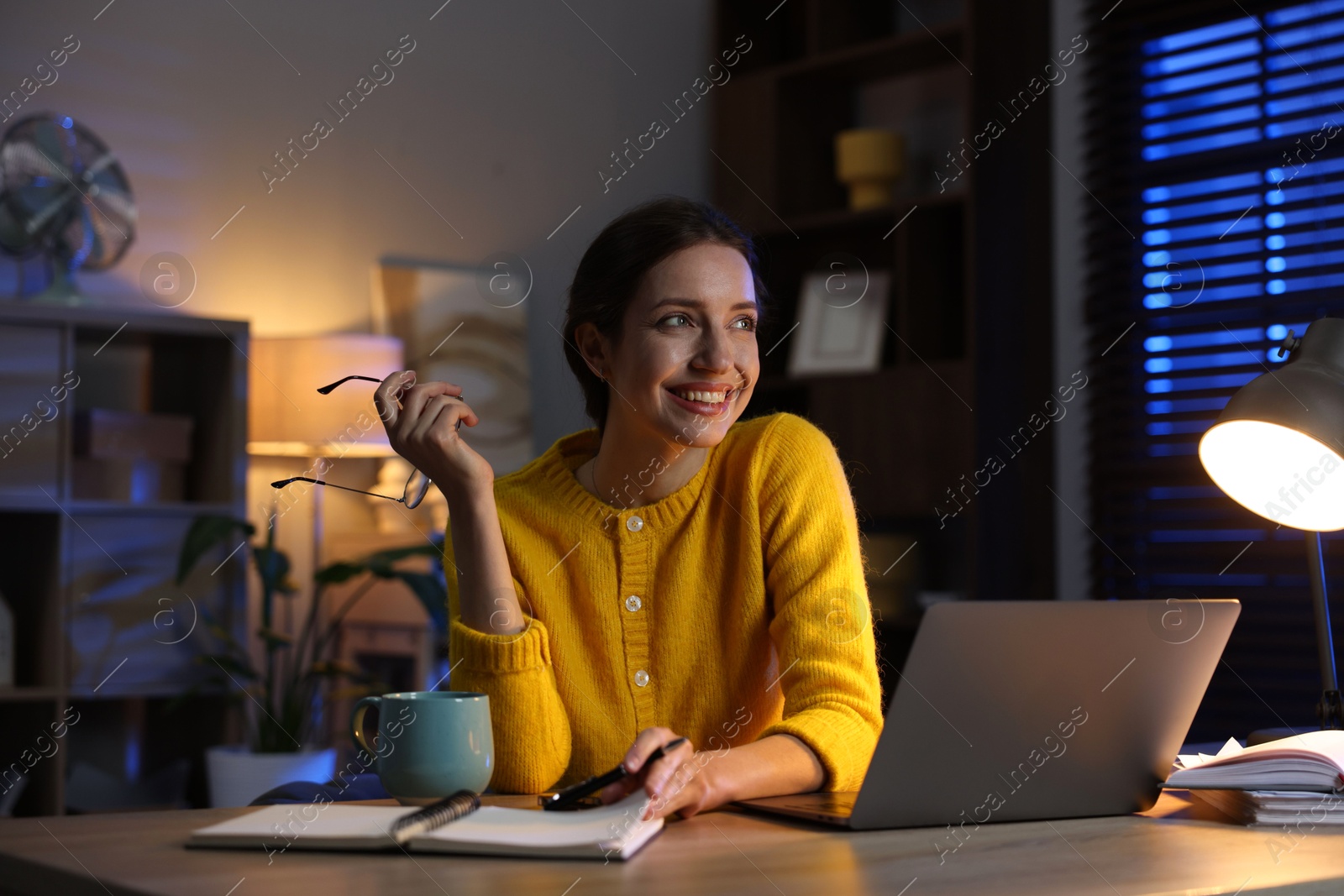 Photo of Woman taking notes while working at desk in home office