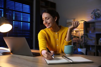 Photo of Woman taking notes while working at desk in home office