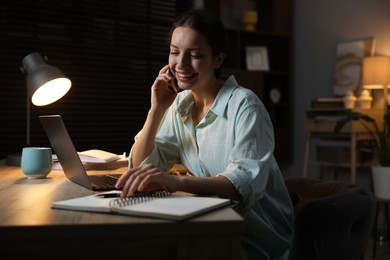 Photo of Woman talking on phone while working at desk in home office