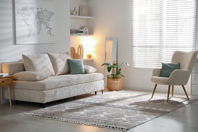 Photo of Comfortable sofa with pillows, armchair and houseplant in living room