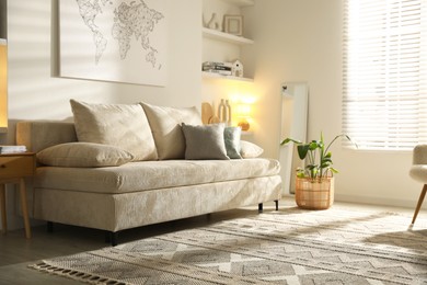 Photo of Comfortable sofa with pillows and houseplant in living room