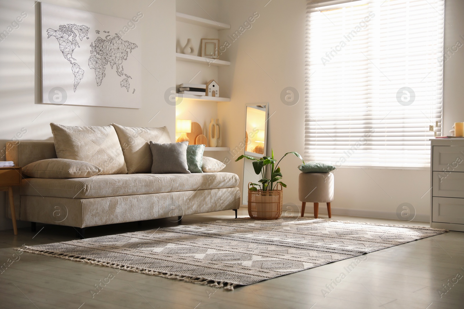 Photo of Comfortable sofa with pillows, pouf and houseplant in living room