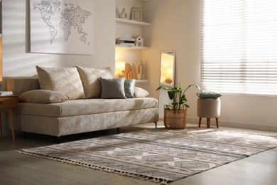 Photo of Comfortable sofa with pillows, pouf and houseplant in living room