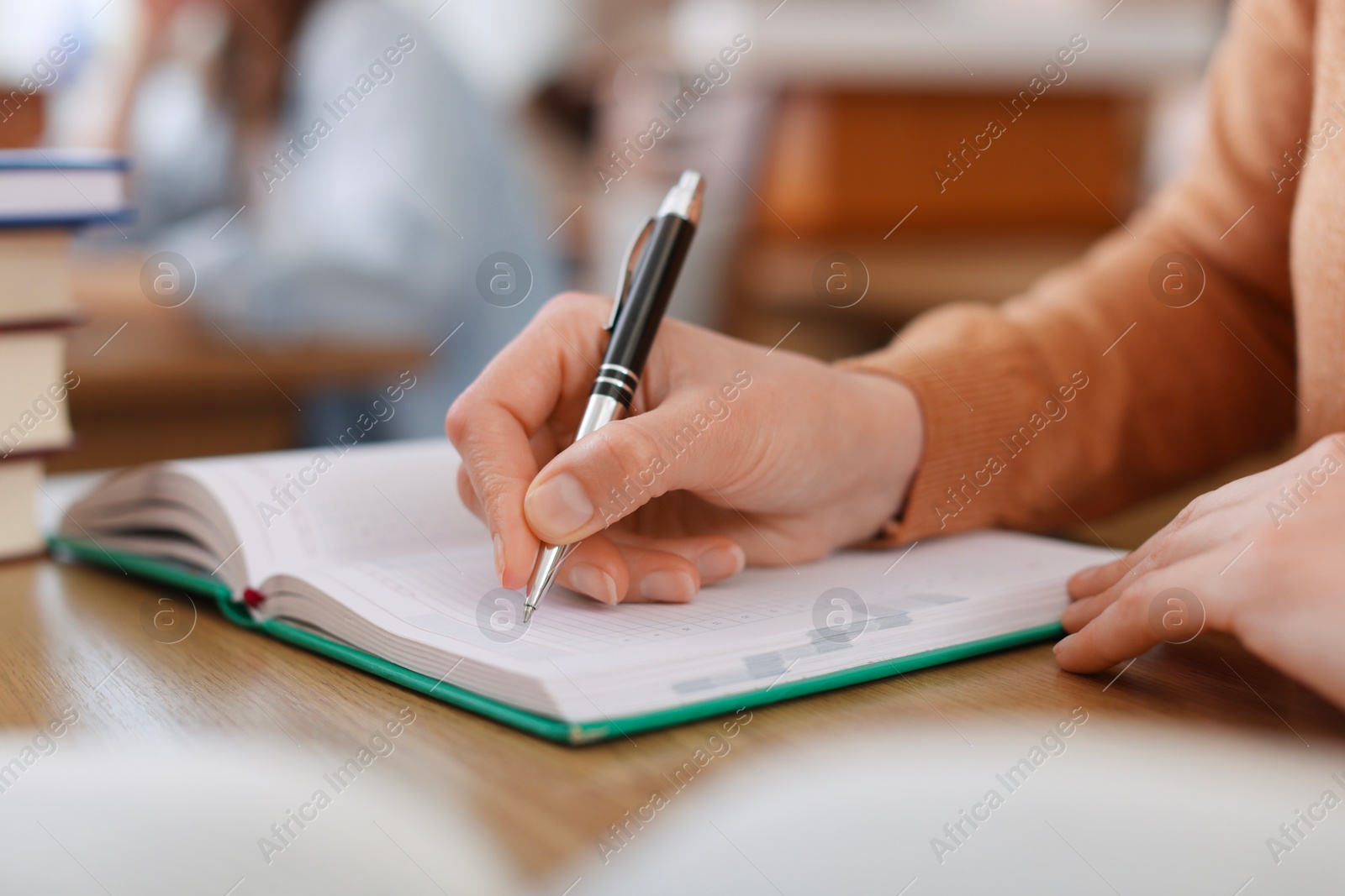 Photo of Woman taking notes at desk in library, closeup