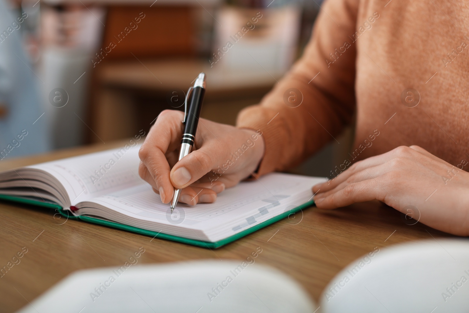 Photo of Woman taking notes at desk in library, closeup