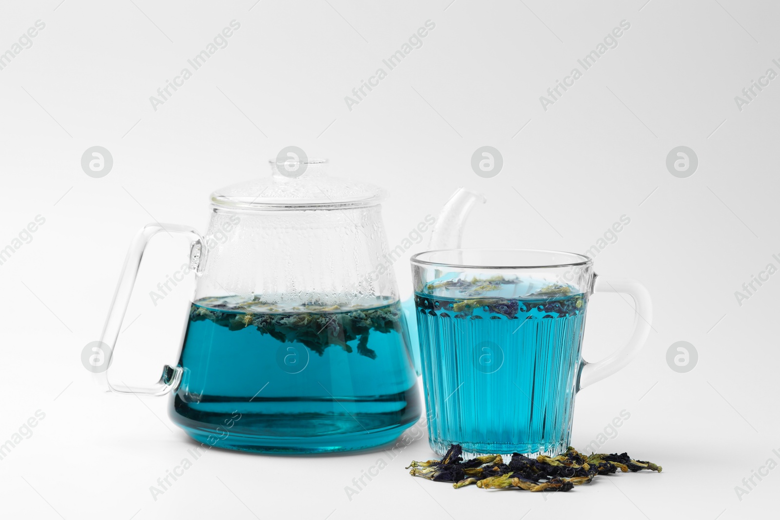 Photo of Fresh butterfly pea flower tea and dry petals on white table, closeup