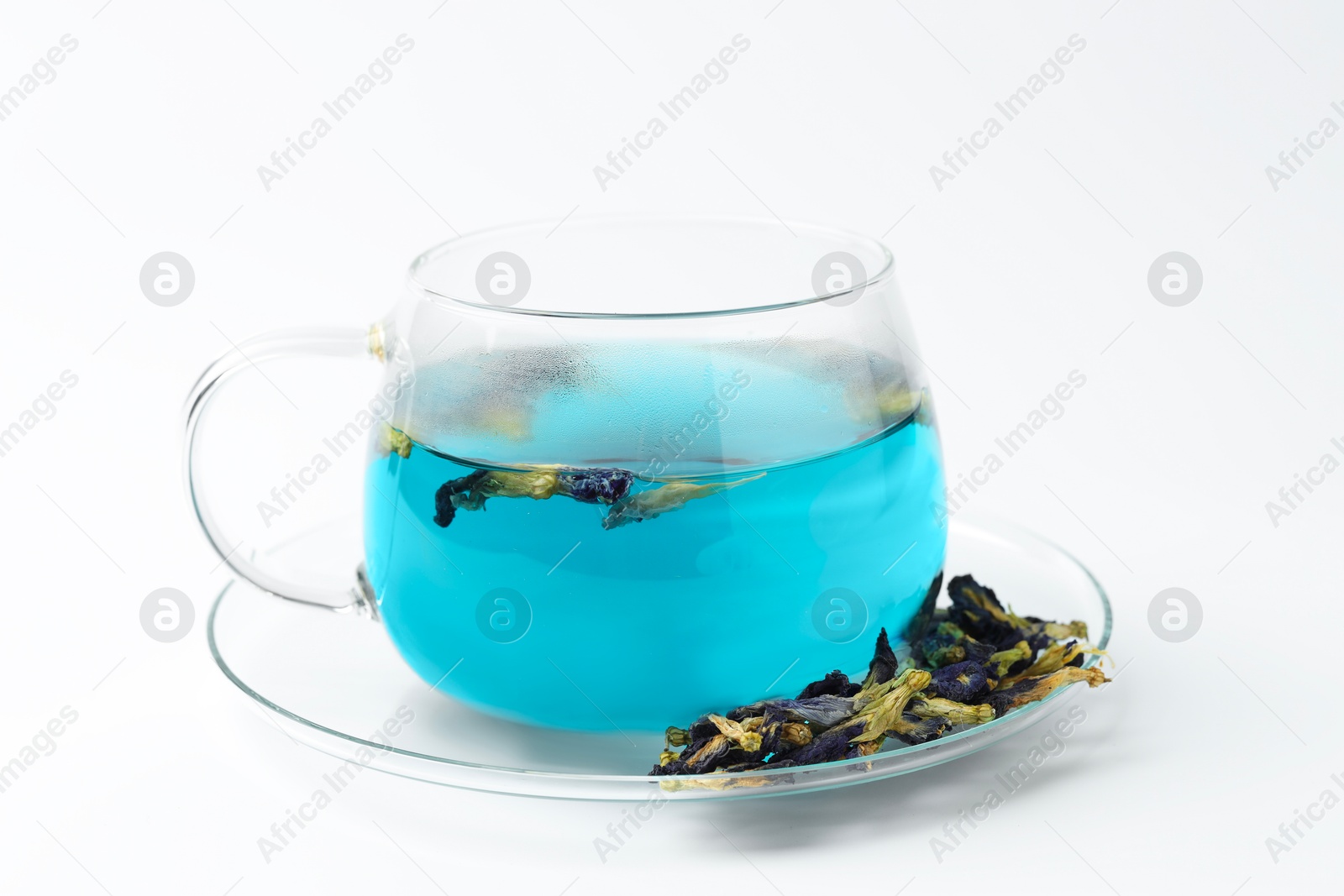 Photo of Fresh butterfly pea flower tea in cup and dry petals on white table, closeup