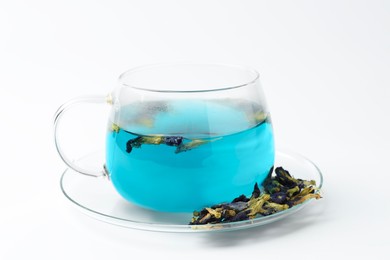 Photo of Fresh butterfly pea flower tea in cup and dry petals on white table, closeup