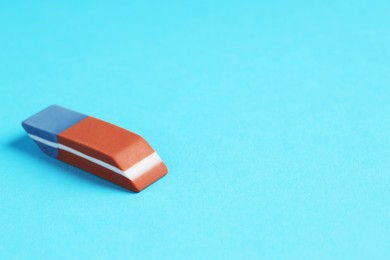 Photo of One eraser on light blue background, closeup. Space for text