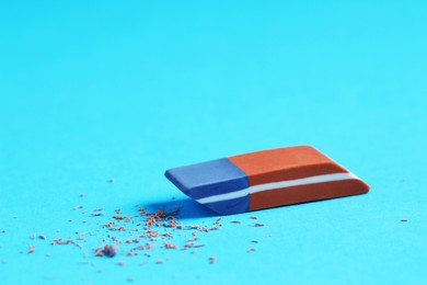 Photo of One eraser and scraps on light blue background, closeup