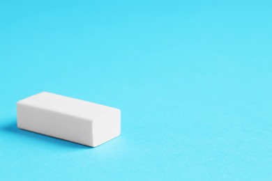 Photo of One eraser on light blue background, closeup. Space for text