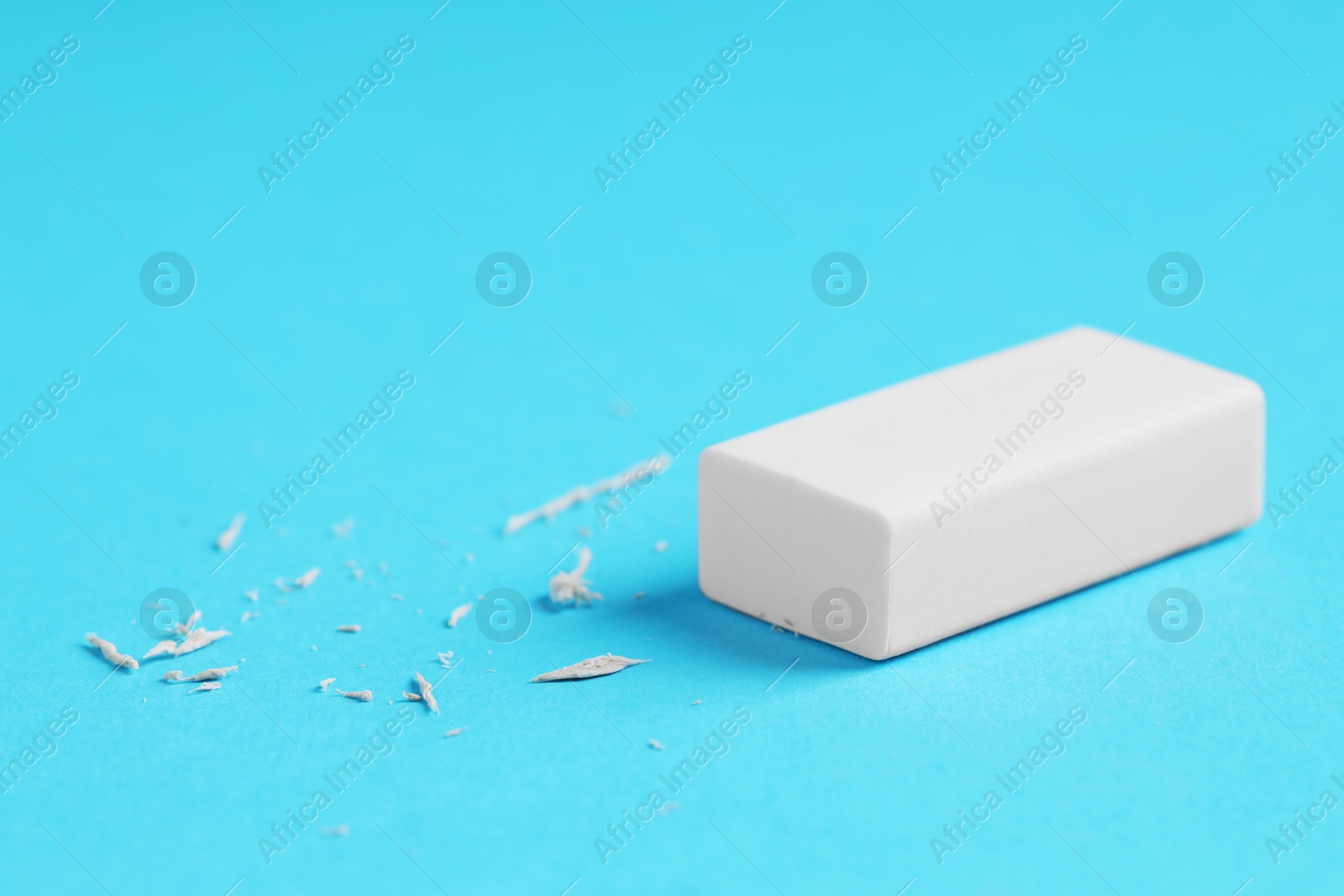 Photo of One eraser and scraps on light blue background, closeup