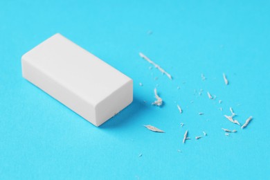 Photo of One eraser and scraps on light blue background, closeup