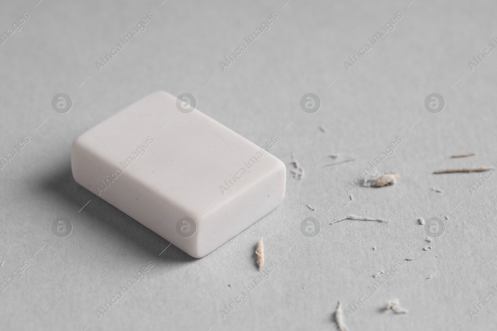 Photo of One eraser and scraps on grey background, closeup