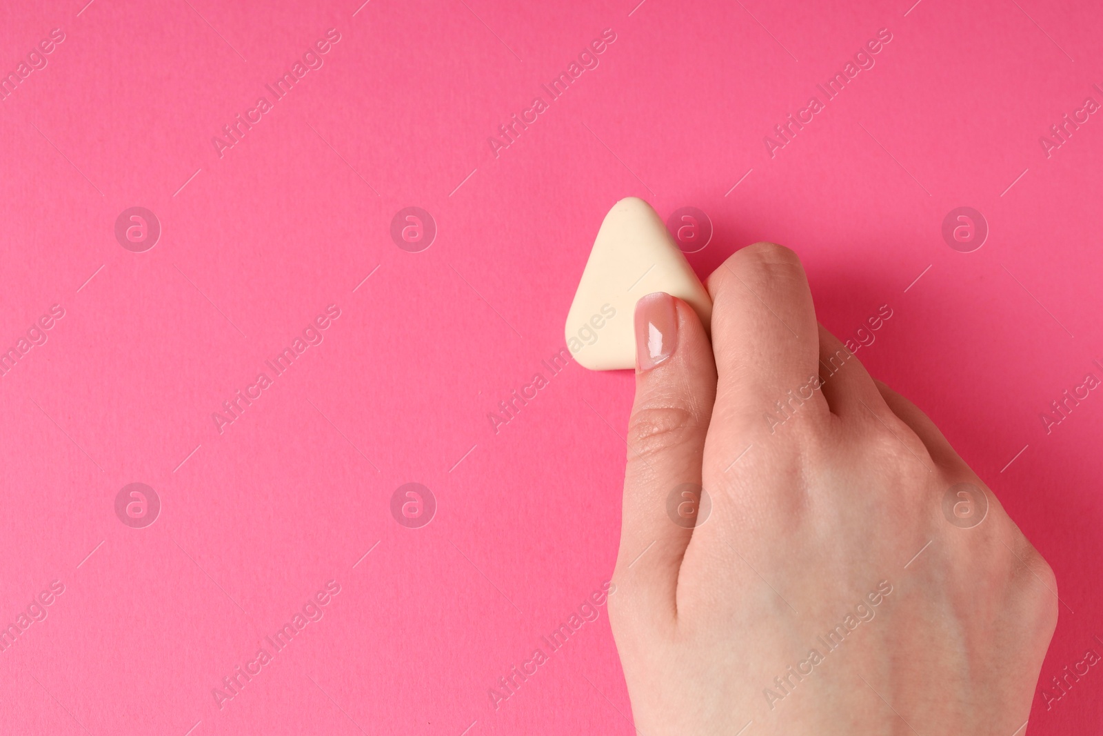 Photo of Woman using eraser on pink background, closeup. Space for text