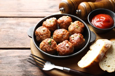 Photo of Tasty meatballs with green onion in baking dish served on wooden table