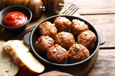 Photo of Tasty meatballs with green onion in baking dish served on wooden table