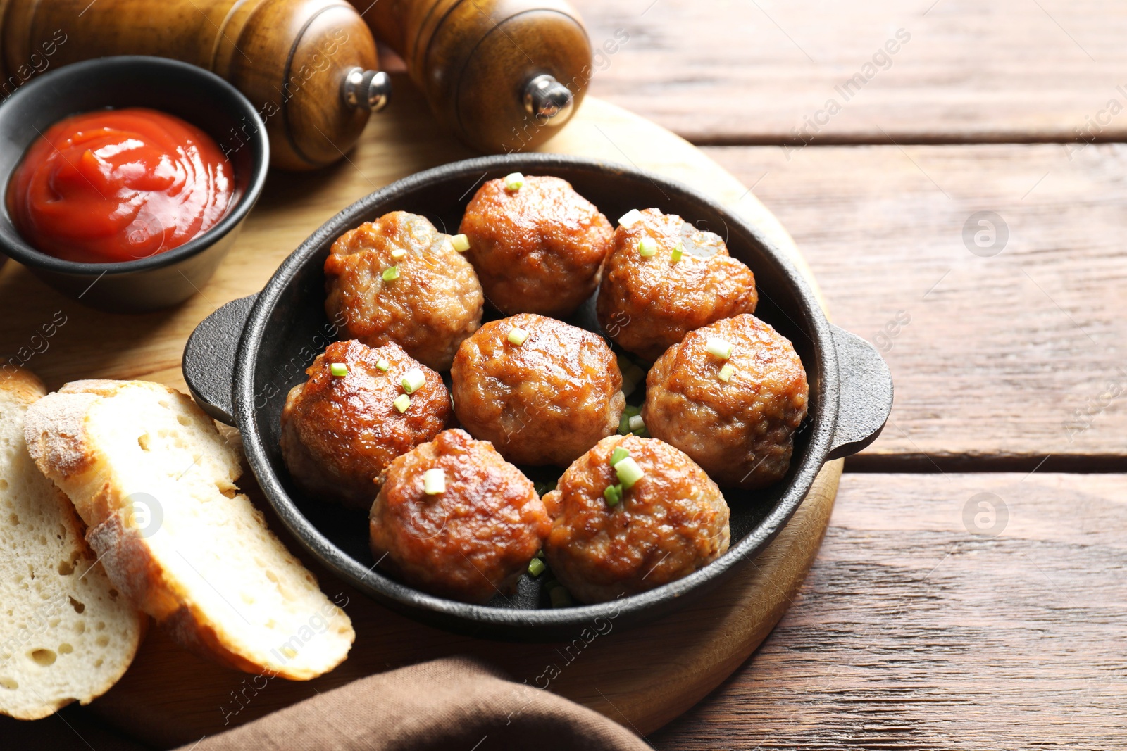 Photo of Tasty meatballs with green onion in baking dish served on wooden table