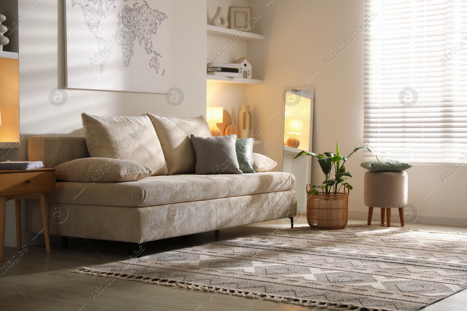 Photo of Comfortable sofa with pillows, pouf and houseplant in living room