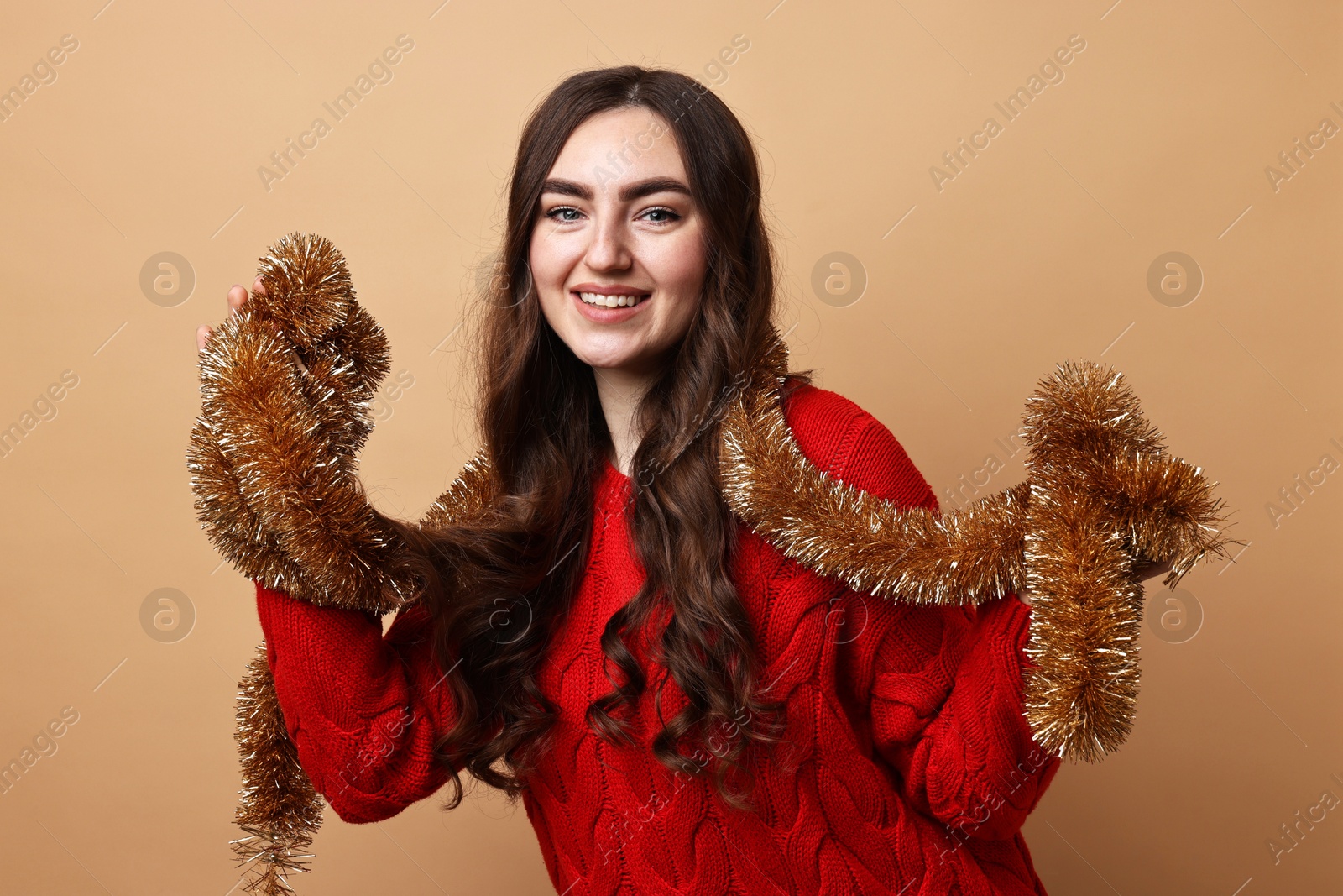 Photo of Happy young woman with tinsel on beige background