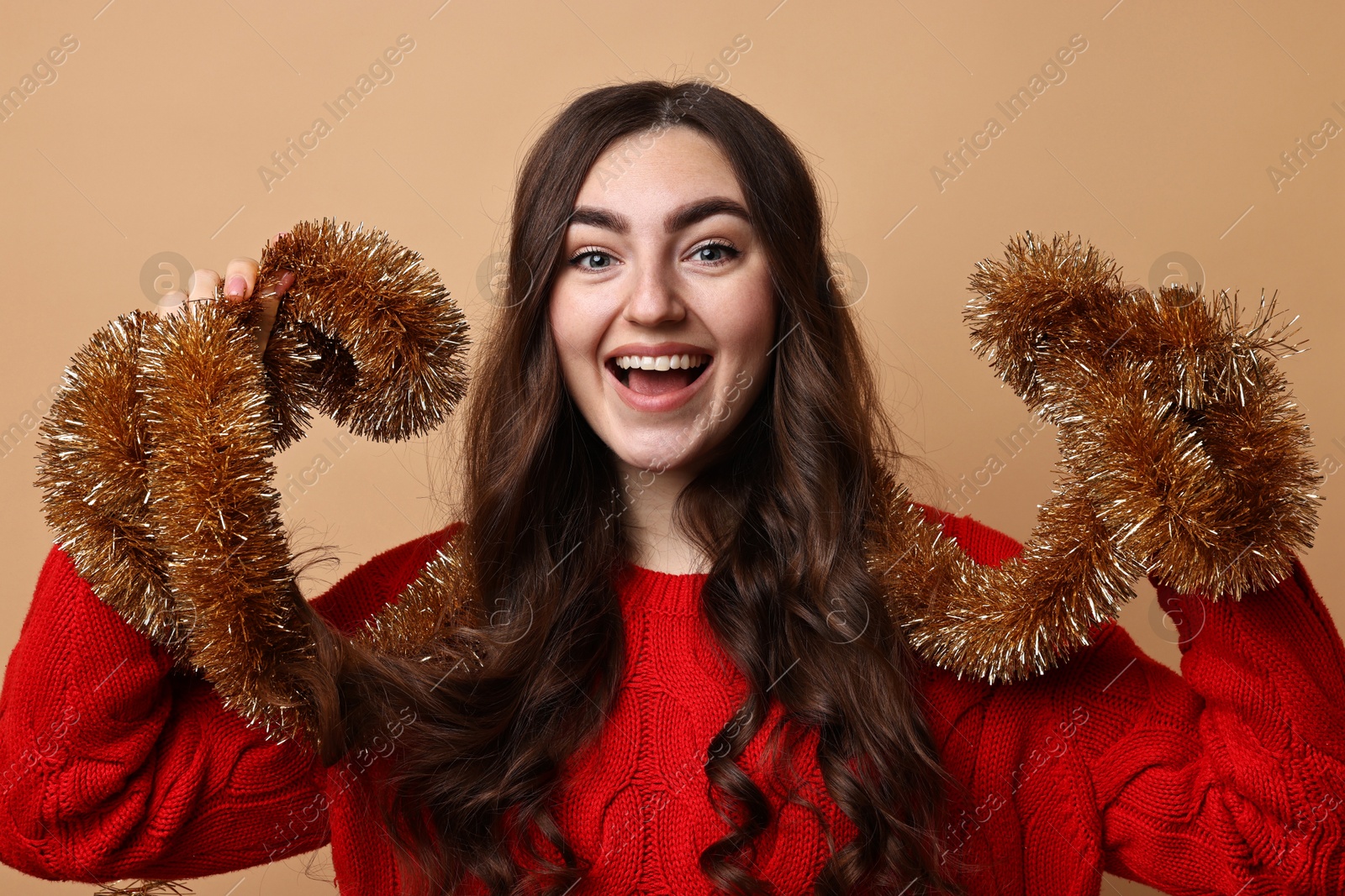 Photo of Happy young woman with tinsel on beige background