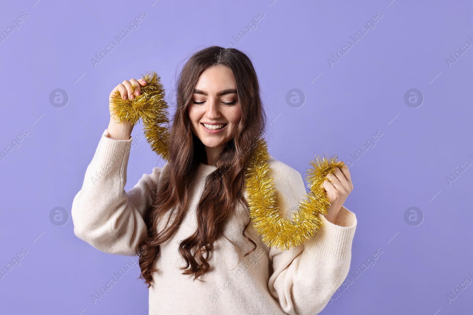 Photo of Happy young woman with tinsel on purple background