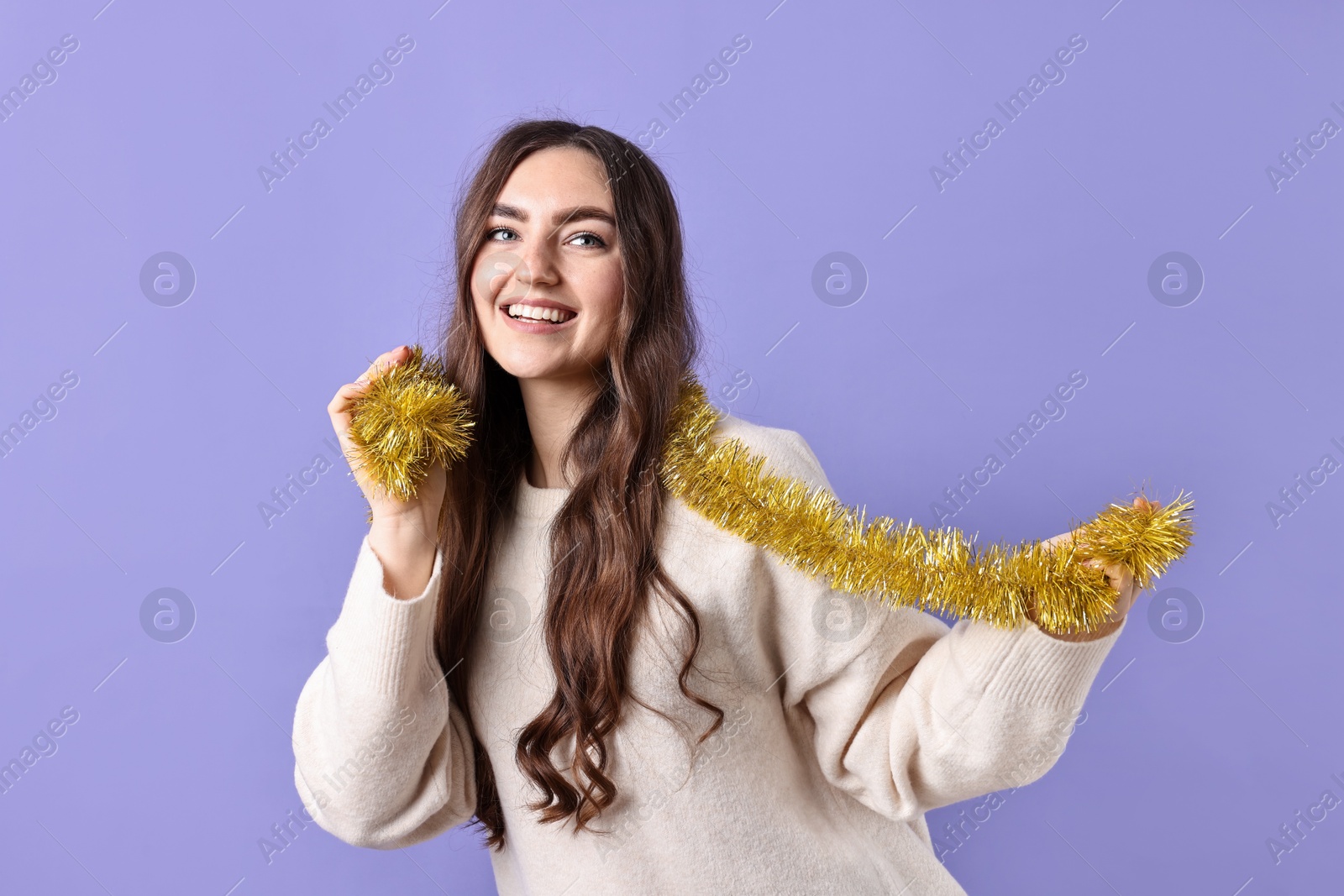 Photo of Happy young woman with tinsel on purple background