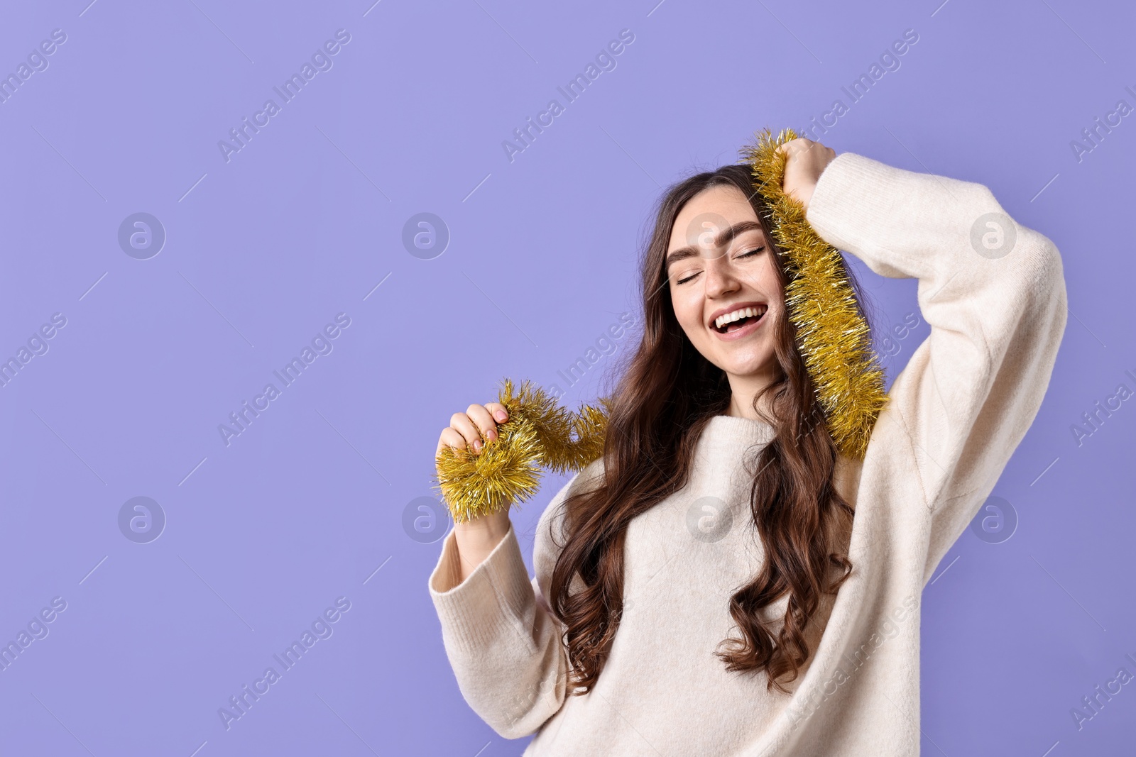 Photo of Happy young woman with tinsel on purple background. Space for text