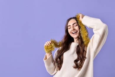 Photo of Happy young woman with tinsel on purple background. Space for text