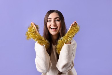 Photo of Happy young woman with tinsel on purple background