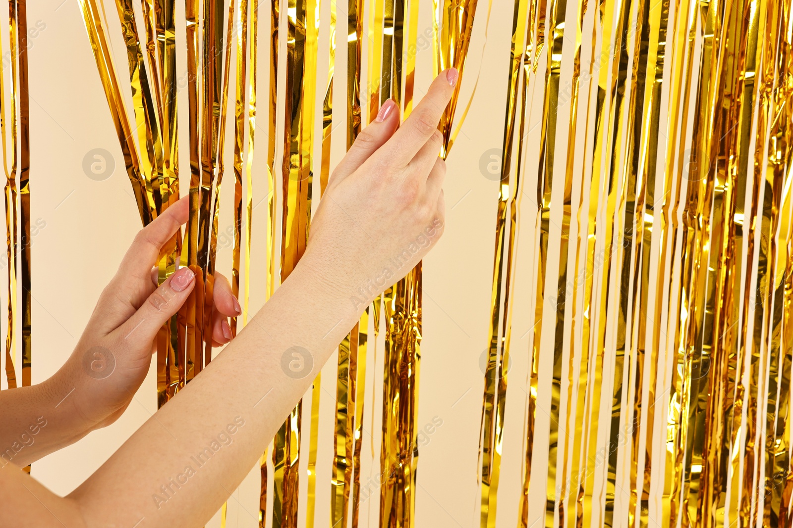 Photo of Woman near golden foil curtain against beige background, closeup