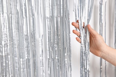 Photo of Woman near silver foil curtain against white background, closeup