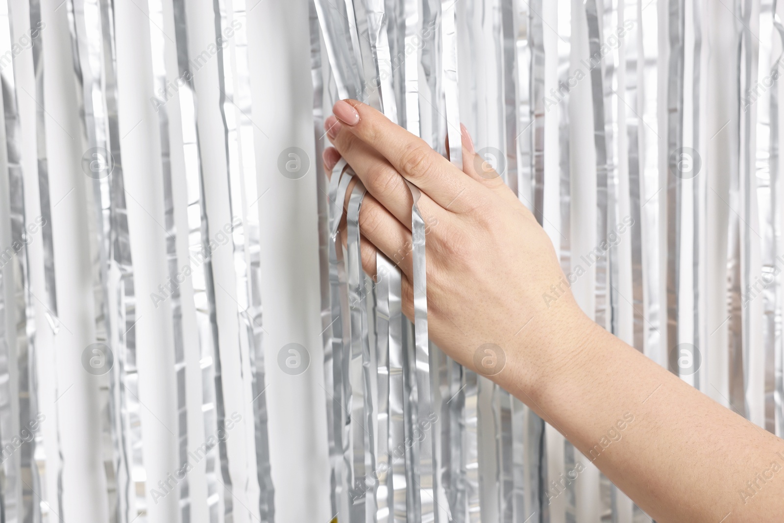 Photo of Woman near silver foil curtain against white background, closeup