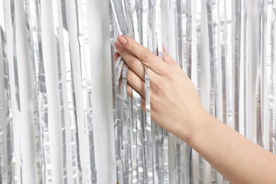 Photo of Woman near silver foil curtain against white background, closeup