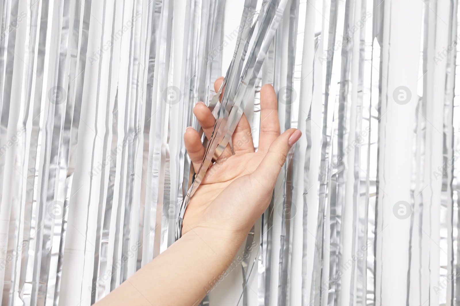 Photo of Woman near silver foil curtain against white background, closeup