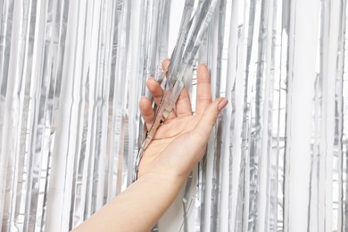 Photo of Woman near silver foil curtain against white background, closeup