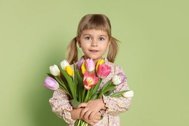 Photo of Cute little girl with bouquet of tulips on green background