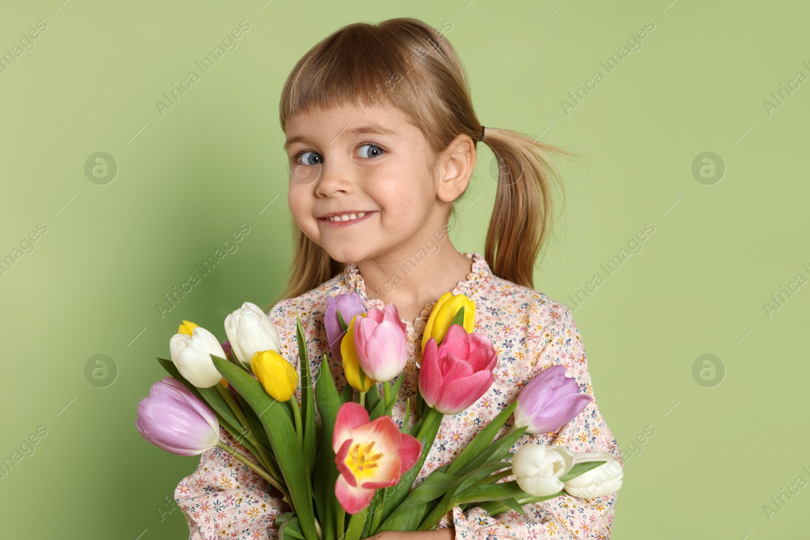 Photo of Smiling little girl with bouquet of tulips on green background