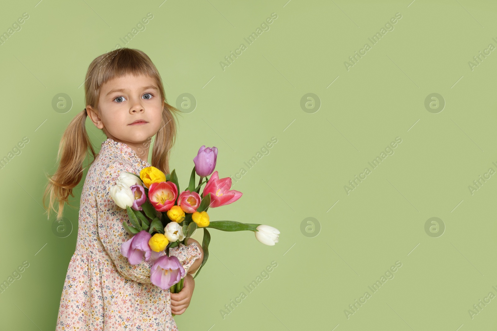 Photo of Cute little girl with bouquet of tulips on green background. Space for text