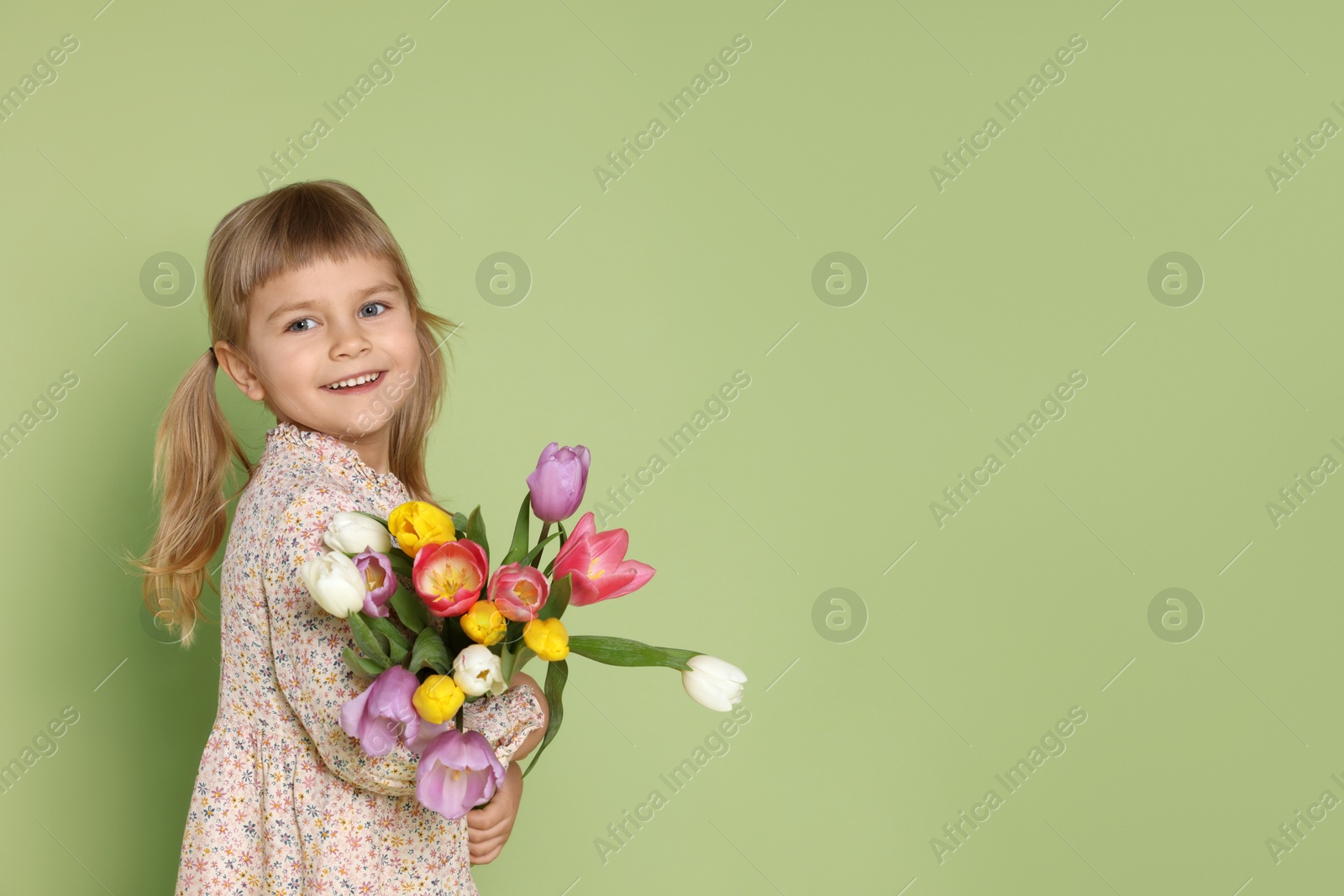 Photo of Smiling little girl with bouquet of tulips on green background. Space for text