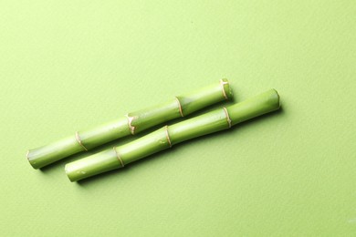 Photo of Cut bamboo stems on light green background, flat lay