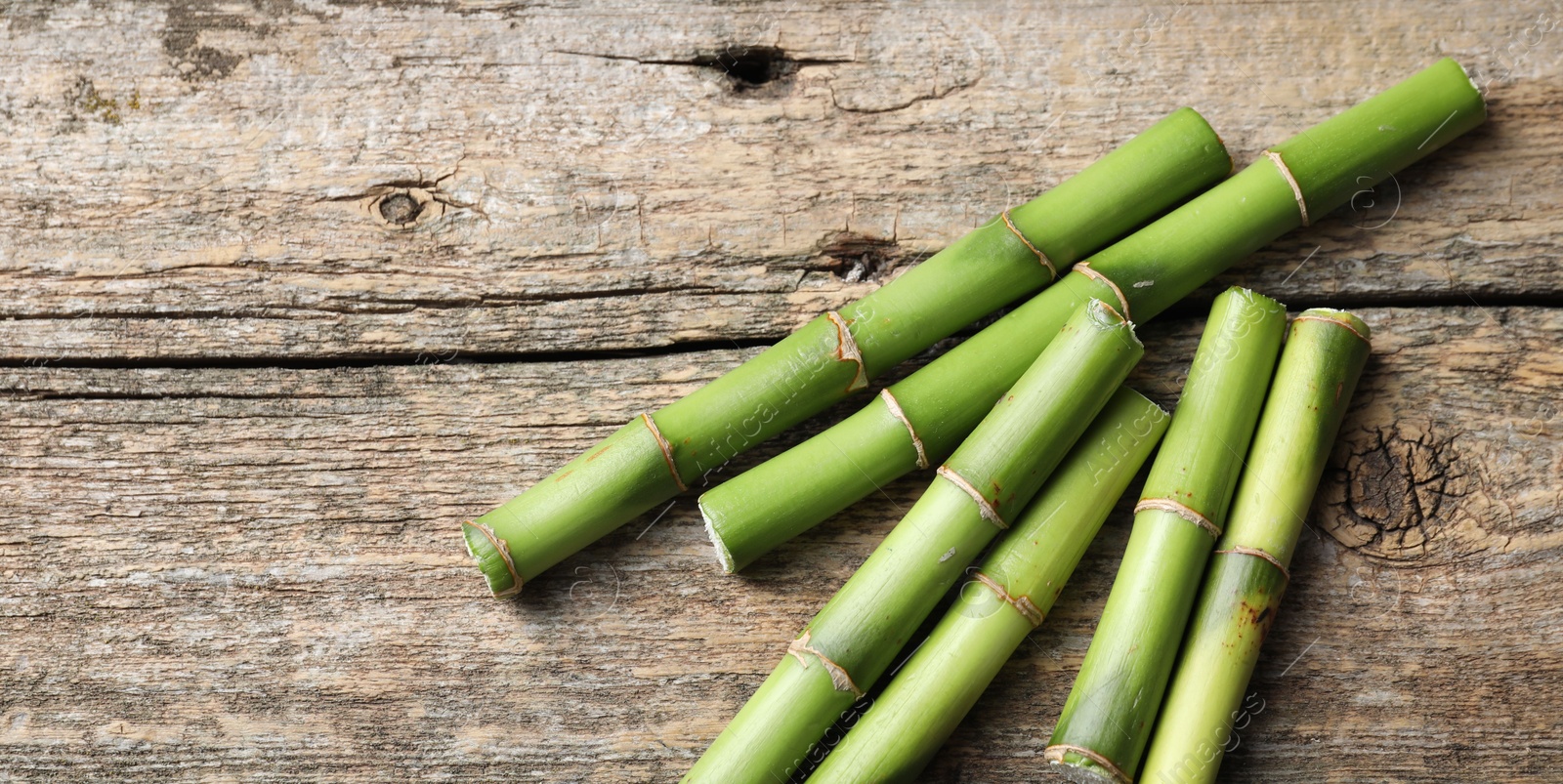 Photo of Cut bamboo stems on wooden table, flat lay. Space for text