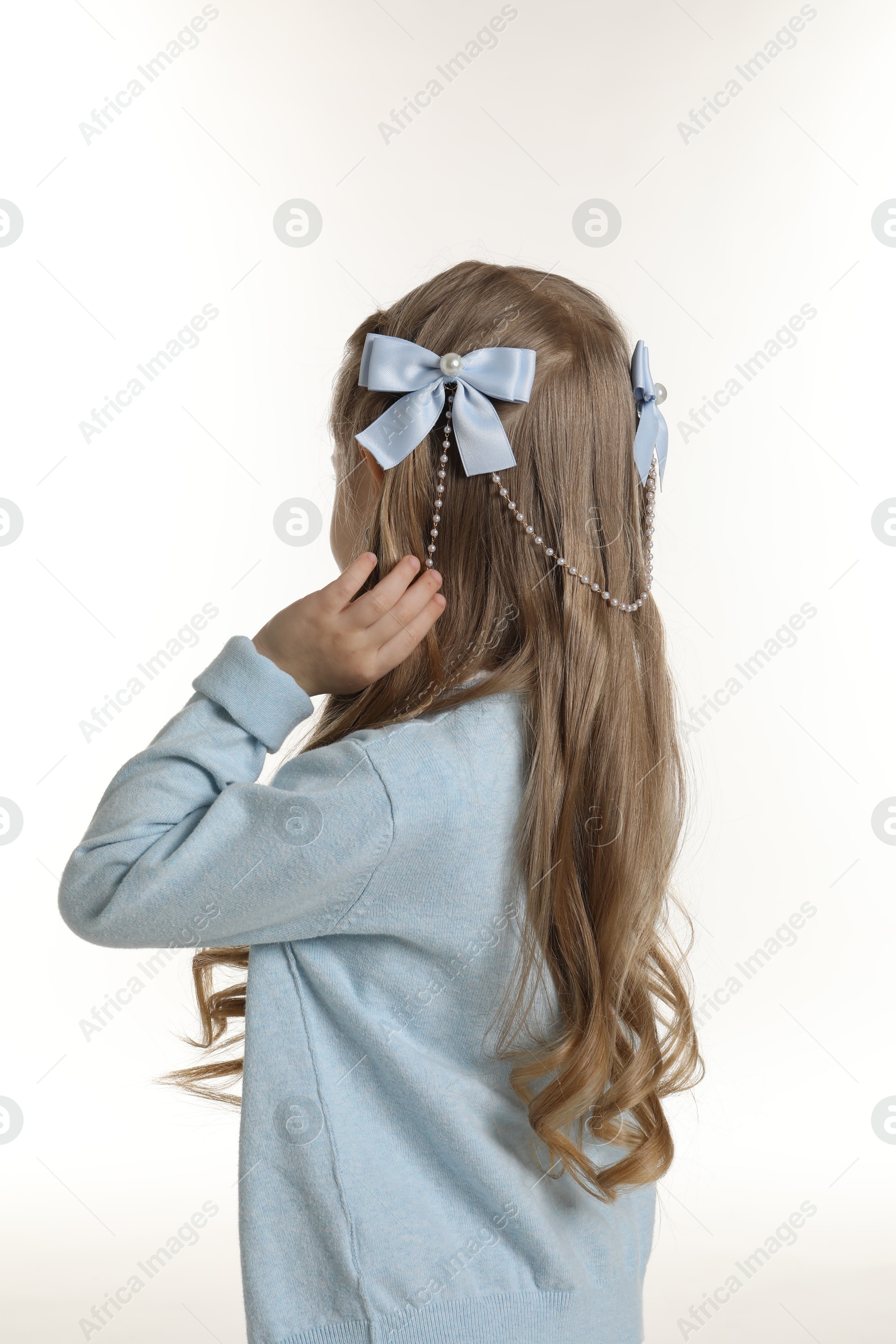 Photo of Cute little girl with beautiful hair accessory on white background, back view