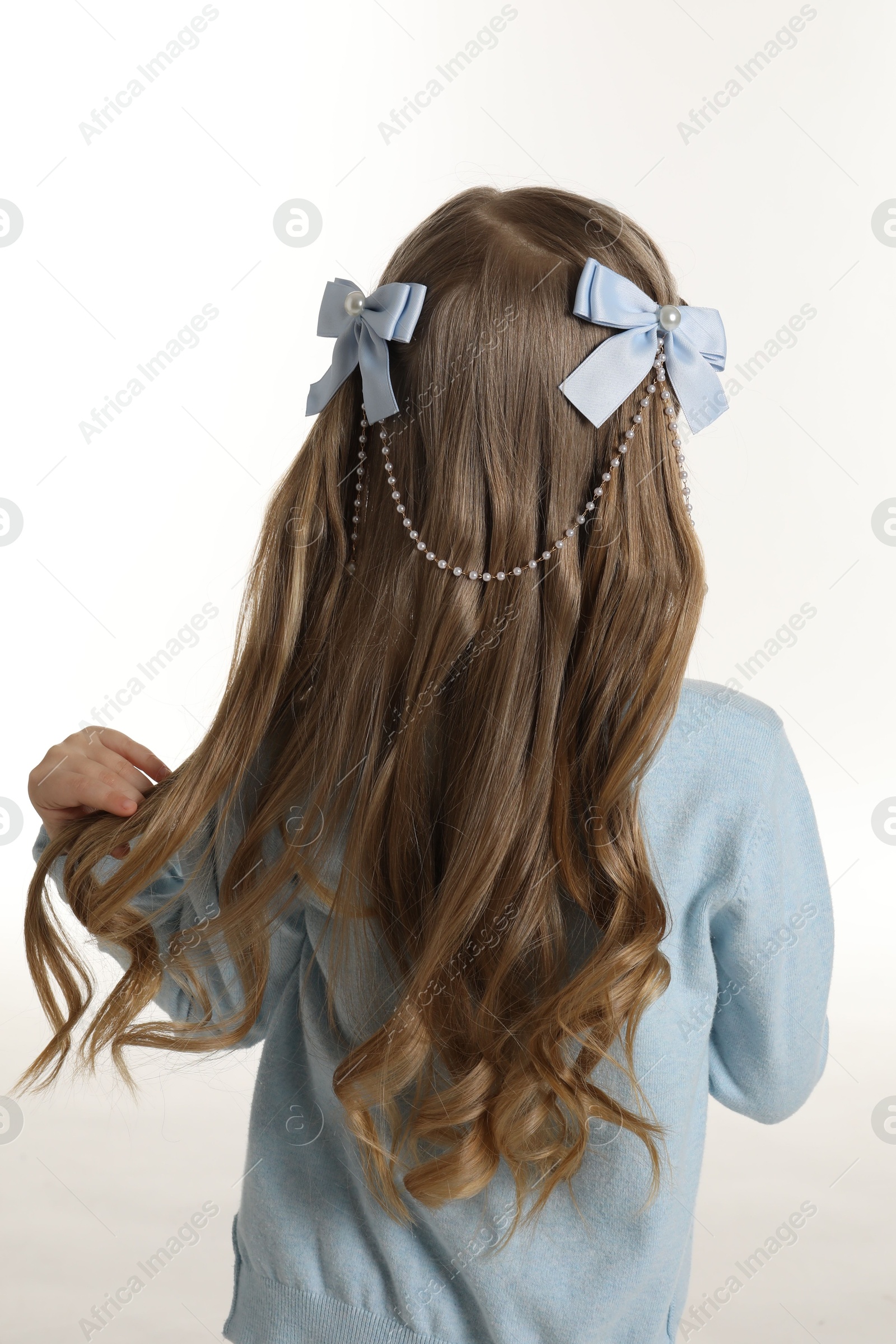 Photo of Cute little girl with beautiful hair accessory on white background, back view