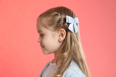 Photo of Cute little girl with beautiful hair accessory on coral background