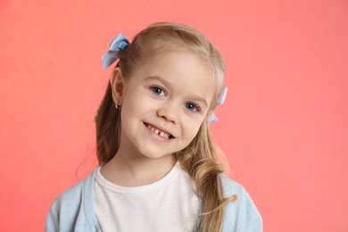 Photo of Cute little girl with beautiful hair accessory on coral background