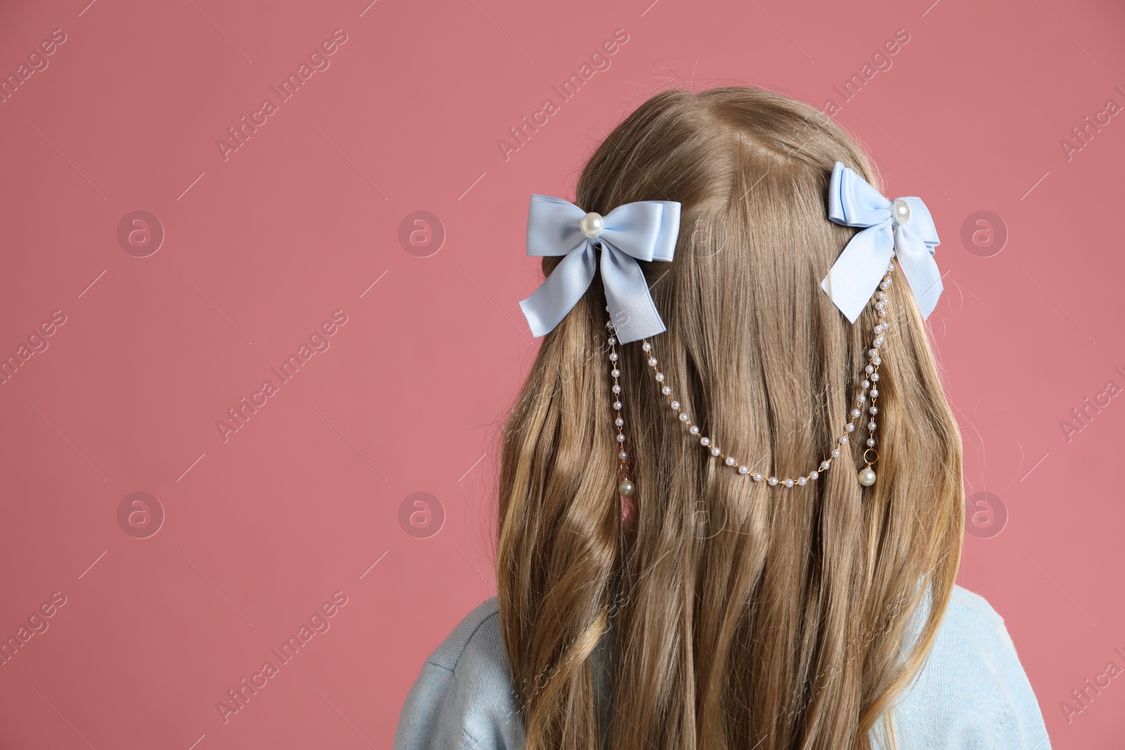 Photo of Cute little girl with beautiful hair accessory on coral background, back view. Space for text